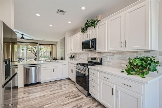 kitchen featuring light wood-type flooring, appliances with stainless steel finishes, ceiling fan, decorative backsplash, and white cabinets