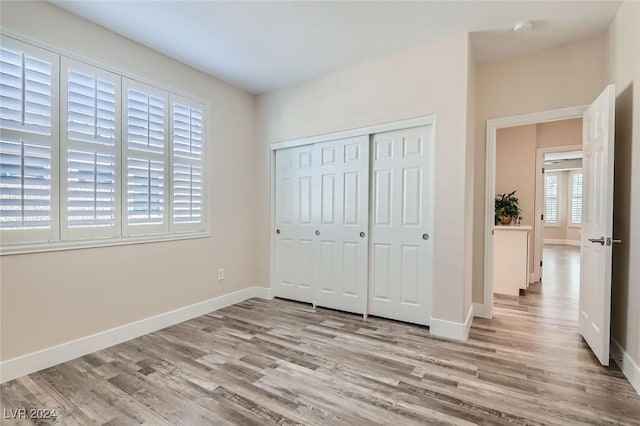 unfurnished bedroom with a closet and light wood-type flooring