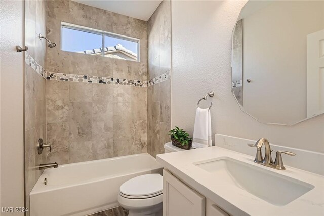 full bathroom with tiled shower / bath, vanity, and toilet