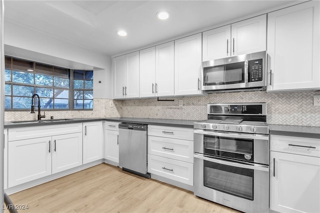 kitchen with sink, white cabinets, stainless steel appliances, and light hardwood / wood-style floors