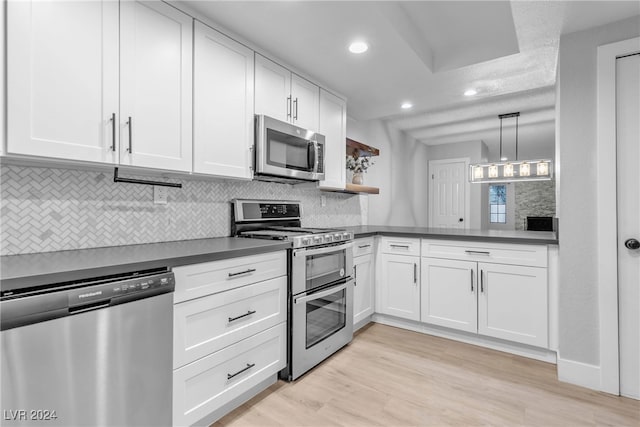 kitchen featuring tasteful backsplash, white cabinetry, pendant lighting, and stainless steel appliances