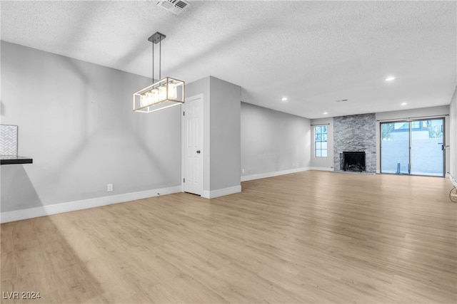 unfurnished living room featuring a textured ceiling, light wood-type flooring, and a fireplace