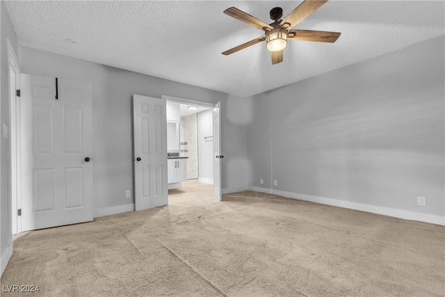 unfurnished bedroom featuring ceiling fan, light colored carpet, and a textured ceiling