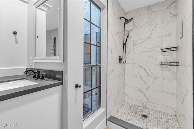 bathroom featuring vanity, a healthy amount of sunlight, and tiled shower