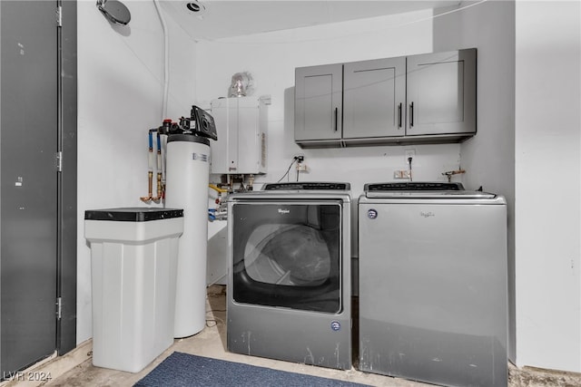 laundry room with cabinets, washing machine and dryer, and water heater