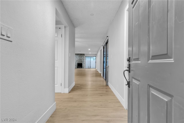 hallway with light hardwood / wood-style floors and a textured ceiling