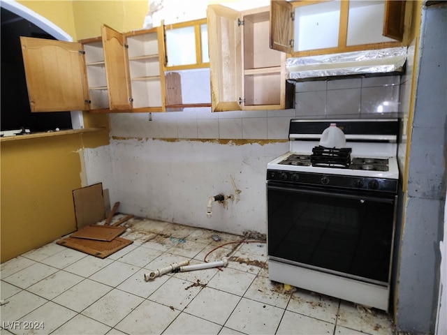 kitchen featuring decorative backsplash, light tile patterned floors, extractor fan, and white gas range oven