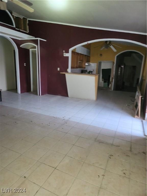 unfurnished living room with a ceiling fan, arched walkways, and crown molding