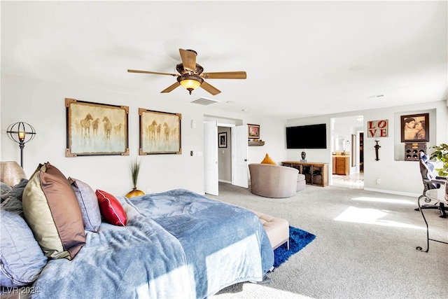 bedroom featuring ceiling fan, light colored carpet, and ensuite bath