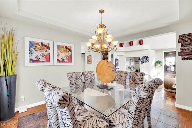 dining area with a raised ceiling, dark hardwood / wood-style flooring, and a chandelier