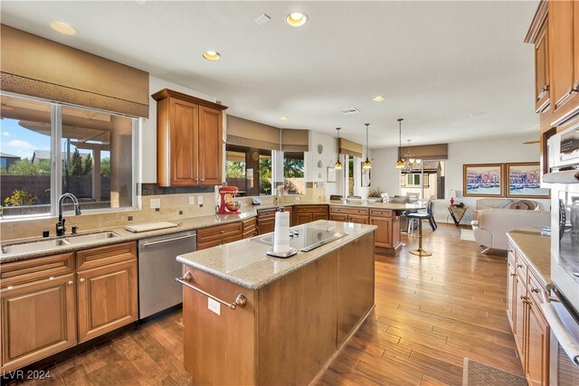 kitchen with dark hardwood / wood-style flooring, decorative light fixtures, a healthy amount of sunlight, and stainless steel dishwasher