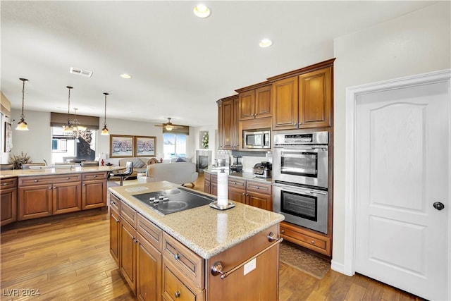 127 Birch Ridge Ave, Las Vegas, NV 89183 - kitchen with stainless steel appliances, a kitchen island, open floor plan, brown cabinetry, and hardwood / wood-style flooring