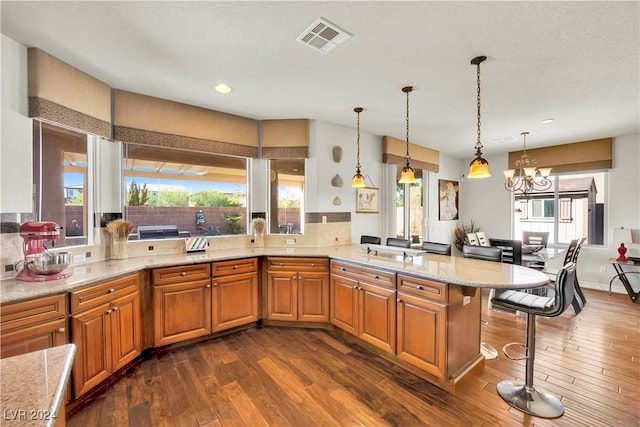 127 Birch Ridge Ave, Las Vegas, NV 89183 - kitchen with a peninsula, a breakfast bar area, a chandelier, brown cabinets, and light stone countertops