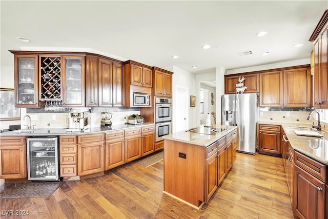 kitchen with light hardwood / wood-style floors, beverage cooler, sink, and stainless steel appliances