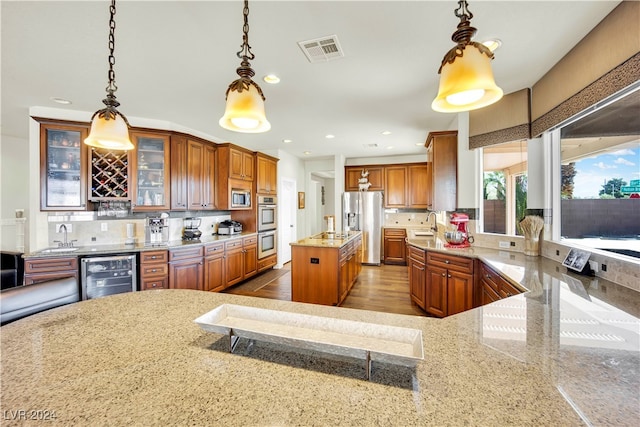 kitchen with wine cooler, hanging light fixtures, tasteful backsplash, stainless steel appliances, and a center island