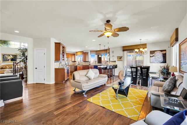 living room featuring ceiling fan with notable chandelier and dark hardwood / wood-style flooring