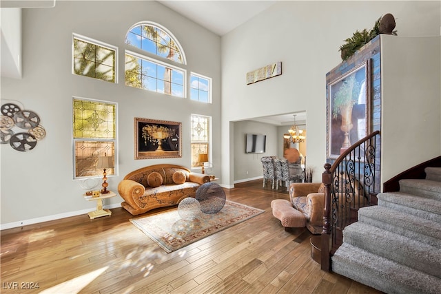 living room with a notable chandelier, a towering ceiling, and hardwood / wood-style floors