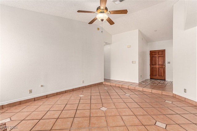 spare room with lofted ceiling, ceiling fan, light tile patterned flooring, and a textured ceiling