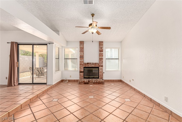 unfurnished living room with a wealth of natural light, ceiling fan, a fireplace, and a textured ceiling