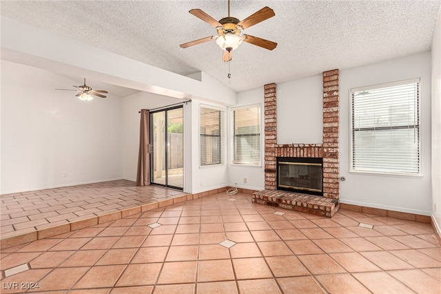 unfurnished living room featuring a brick fireplace, ceiling fan, light tile patterned flooring, and a textured ceiling