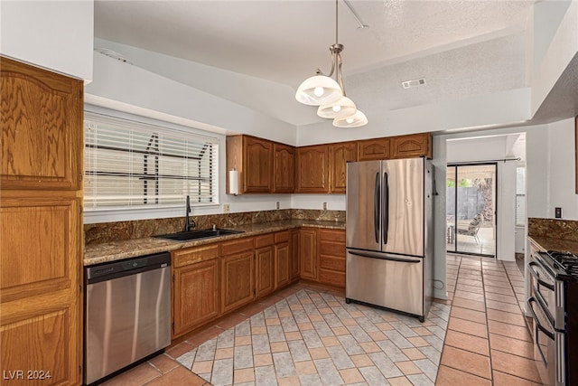 kitchen with hanging light fixtures, sink, a textured ceiling, appliances with stainless steel finishes, and vaulted ceiling