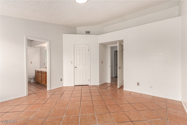 tiled empty room with a textured ceiling