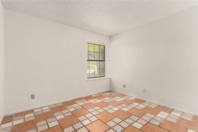 spare room featuring a textured ceiling and light tile patterned flooring