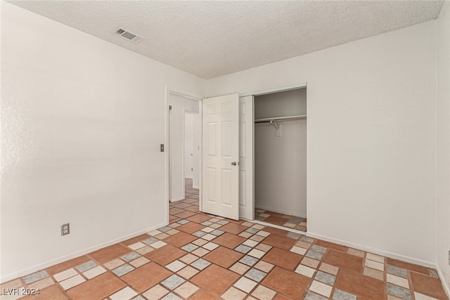 unfurnished bedroom with a closet, light tile patterned flooring, and a textured ceiling