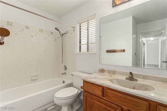 full bathroom featuring tiled shower / bath combo, vanity, and toilet