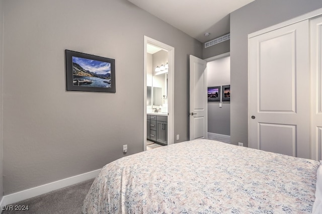 carpeted bedroom featuring sink, a closet, and ensuite bathroom