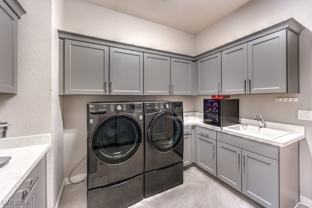 clothes washing area featuring cabinets, washer and dryer, and sink