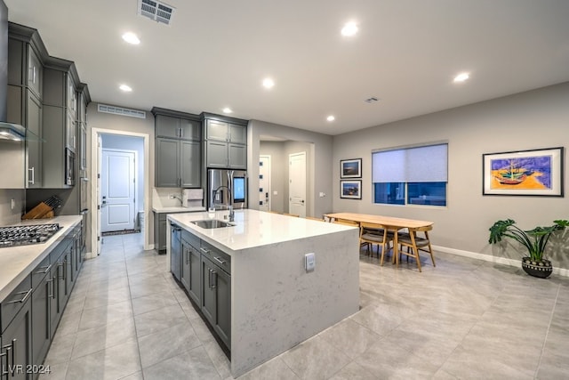 kitchen featuring sink, an island with sink, gray cabinetry, appliances with stainless steel finishes, and light tile patterned floors