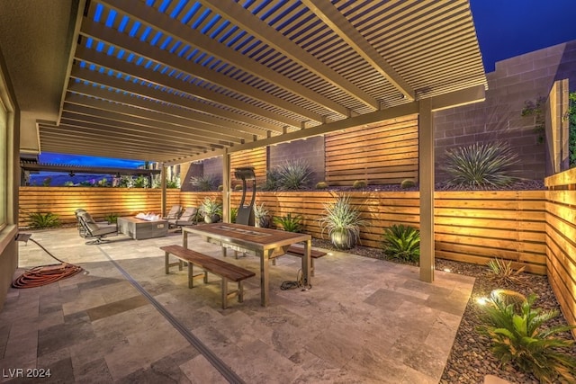 patio at night with a fire pit and a pergola