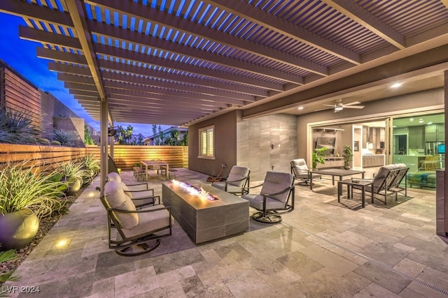 patio at night with ceiling fan, an outdoor living space with a fire pit, and a pergola