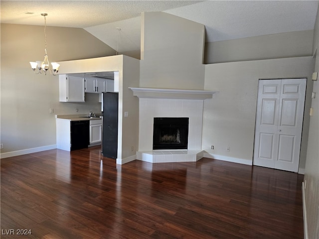 unfurnished living room featuring high vaulted ceiling, a tile fireplace, a textured ceiling, an inviting chandelier, and dark hardwood / wood-style floors