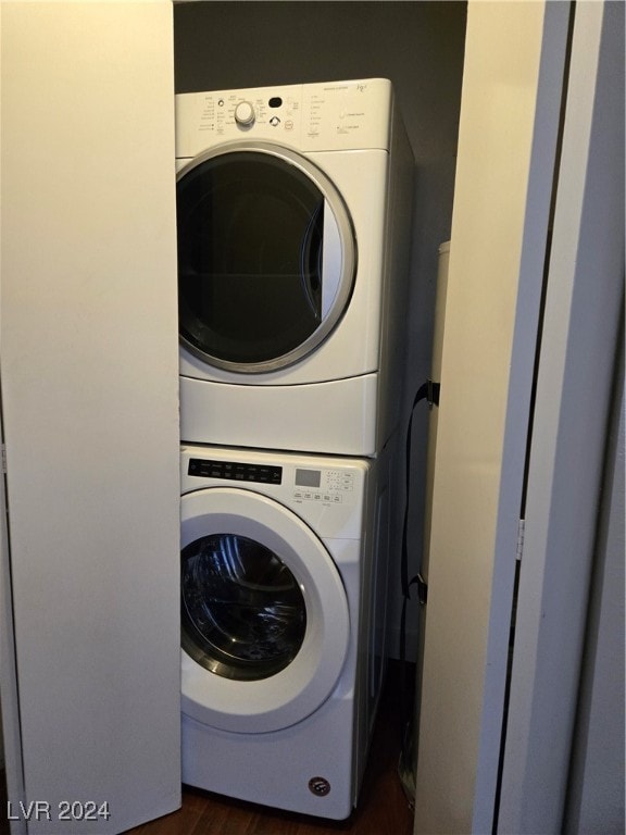 laundry area with stacked washer / dryer and dark hardwood / wood-style flooring