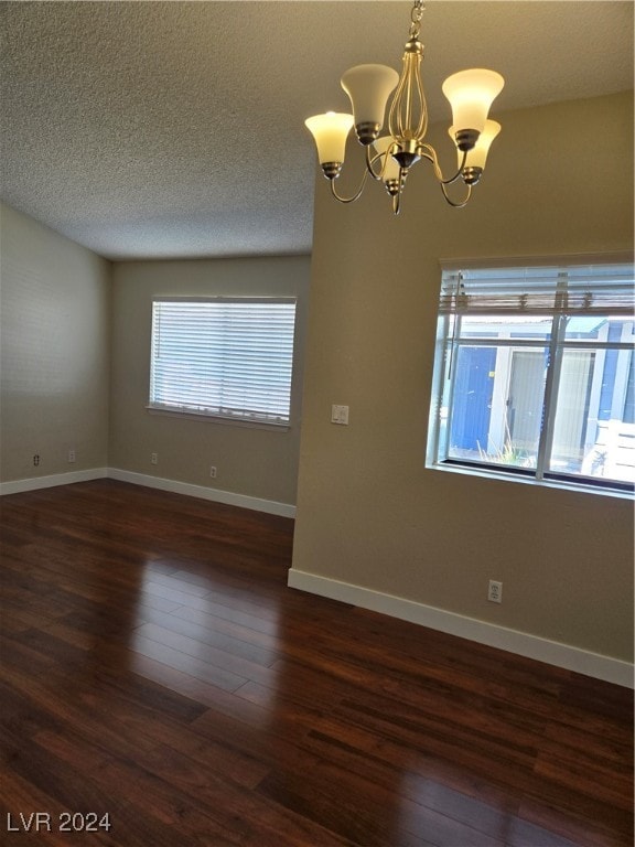 unfurnished room featuring a notable chandelier, a textured ceiling, and dark hardwood / wood-style floors