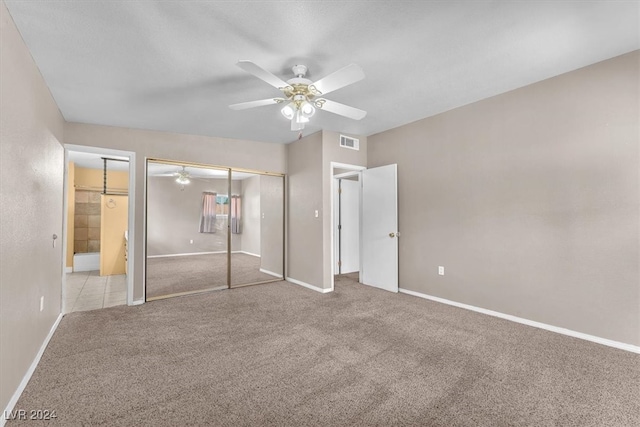 unfurnished bedroom featuring light carpet, ensuite bath, and ceiling fan