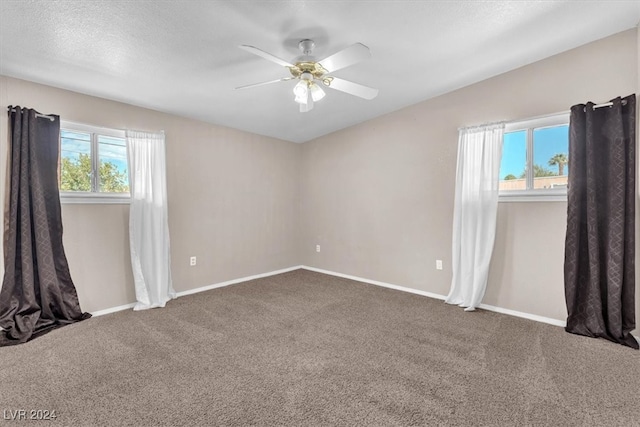 carpeted spare room with a textured ceiling, ceiling fan, and plenty of natural light