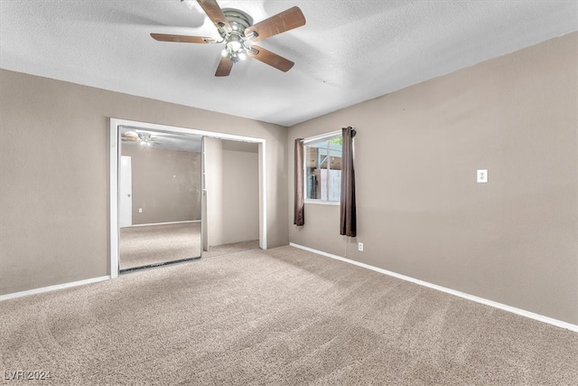 unfurnished bedroom with ceiling fan, light colored carpet, a textured ceiling, and a closet