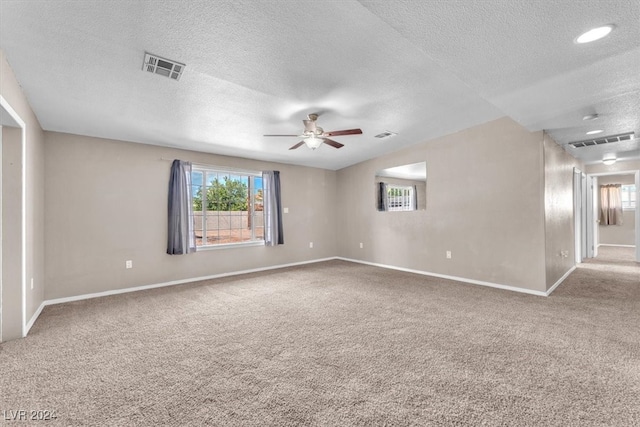 carpeted spare room featuring a textured ceiling and ceiling fan