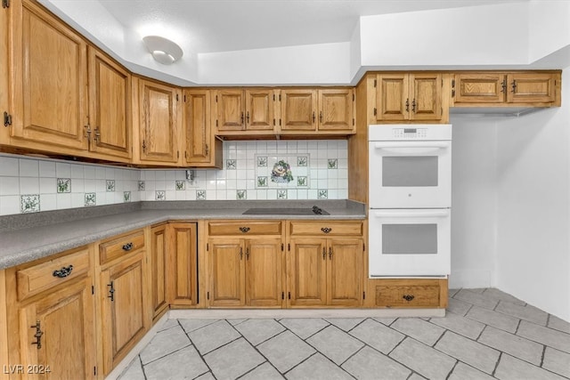 kitchen with black electric cooktop, double oven, vaulted ceiling, and tasteful backsplash