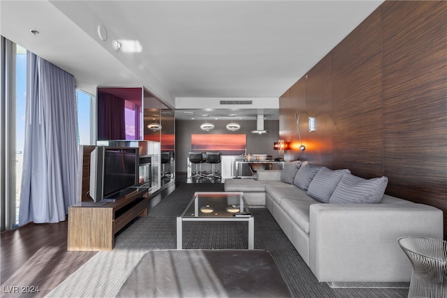 living room featuring wooden walls, dark wood-type flooring, and expansive windows