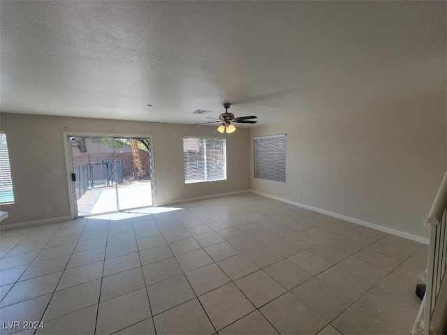 empty room featuring light tile patterned floors, a textured ceiling, ceiling fan, visible vents, and baseboards