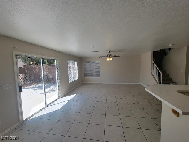 unfurnished living room featuring a textured ceiling, ceiling fan, and light tile patterned floors