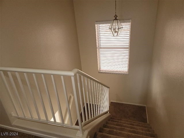 stairway featuring a textured wall and a chandelier