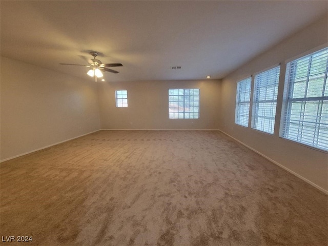 carpeted spare room featuring visible vents, a ceiling fan, and baseboards