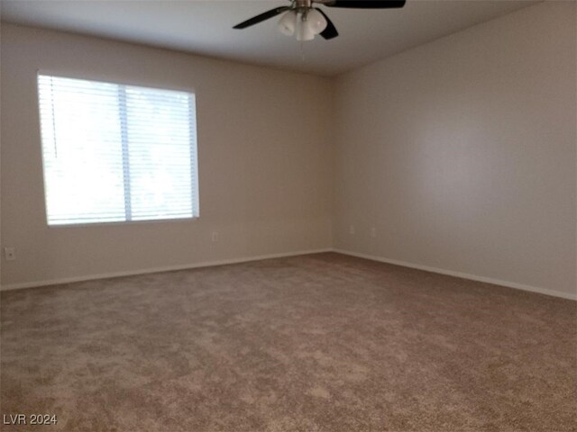 carpeted spare room featuring baseboards and a ceiling fan