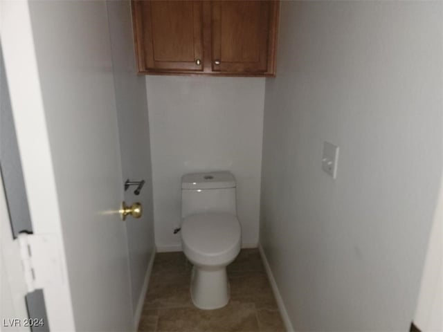 bathroom featuring baseboards, tile patterned floors, and toilet