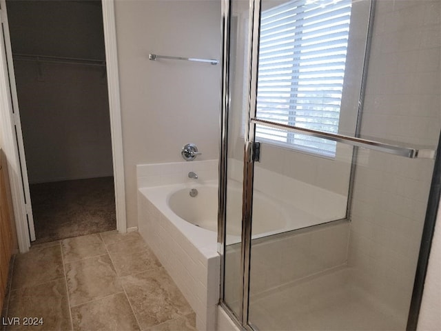 full bath featuring a bath, a shower stall, tile patterned floors, and a spacious closet